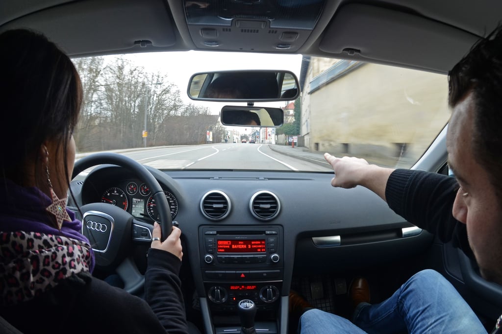 Eine Fahrschülerin sitzt in einem Fahrschulauto neben ihrem Fahrlehrer.