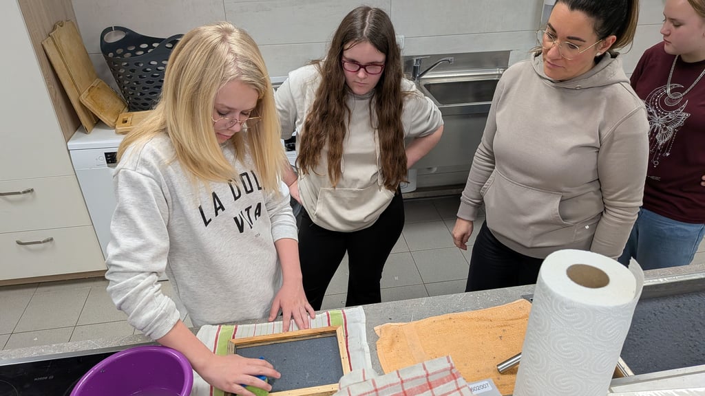 Schülerinnen beim Schöpfen von Papier.