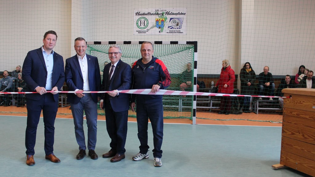 Tim Teßmann (CDU, von links), Bernhard Hieber (SPD), Klaus Zimmermann (CDU) und Torsten Fieseler (KSB Börde) schneiden symbolisch das Absperrband in der Sporthalle „Zollstraße“ zur Wiedereröffnung durch. 
