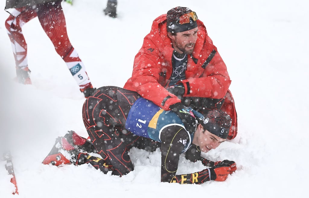 Vinzenz Geiger liegt im Schnee und wird von Teamkollege Johannes Rydzek getröstet.