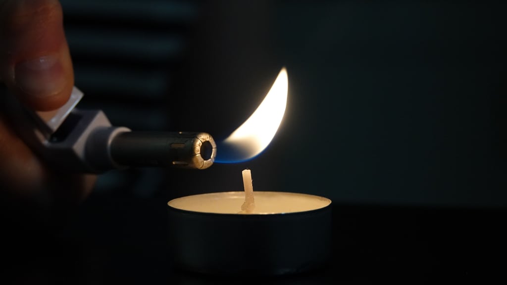 Eine Frau zündet mit dem Feuerzeug ein Teelicht an.