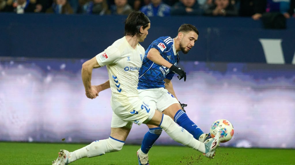 Das 1:0 für Schalke: Adil Aouchiche schießt, Magdeburgs Jean Hugonet fälscht mit der Fußspitze ab - und der Ball fliegt im hohen Bogen ins Tor.