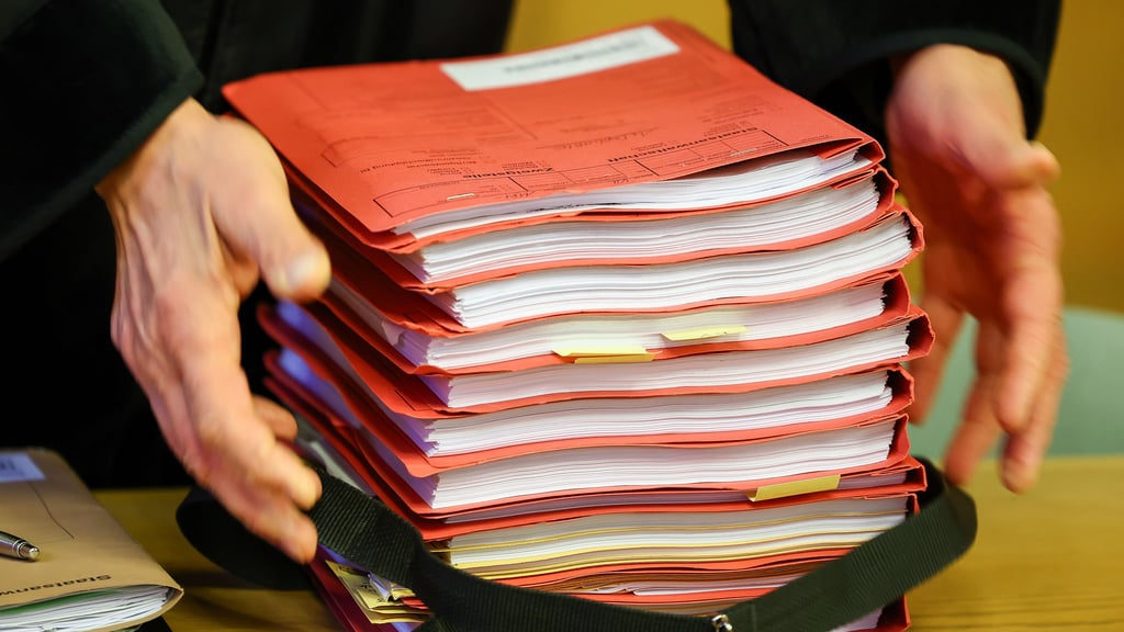 Ein Staatsanwalt legt einen Aktenstapel im Landgerichtssaal ab.