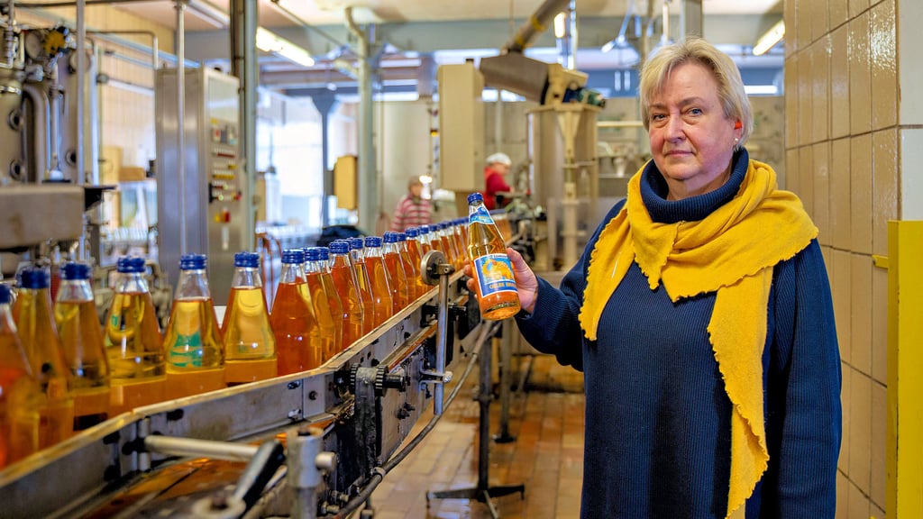 Neben der laufenden Abfüllanlage hält Geschäftsführerin Susann Danneberg den Bestseller der „Dinobrause“ in der Hand.