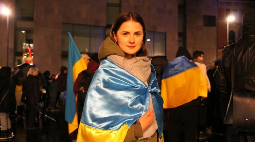 Eine junge Frau hüllte sich bei einer Kundgebung zum ersten Jahrestag des russischen Angriffs auf dem halleschen Markt in eine ukrainische Flagge. Auch am Dienstag wird es wieder eine Kundgebung geben.&nbsp;