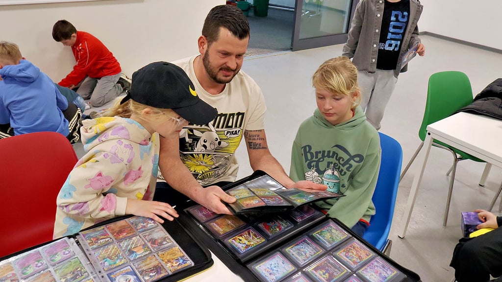 Von links Elies Hamann (8), Vater Michael Hamann (41) und Sammlerin Marie Johanna Brösel (7) vergleichen und tauschen die Sammelkarten. 