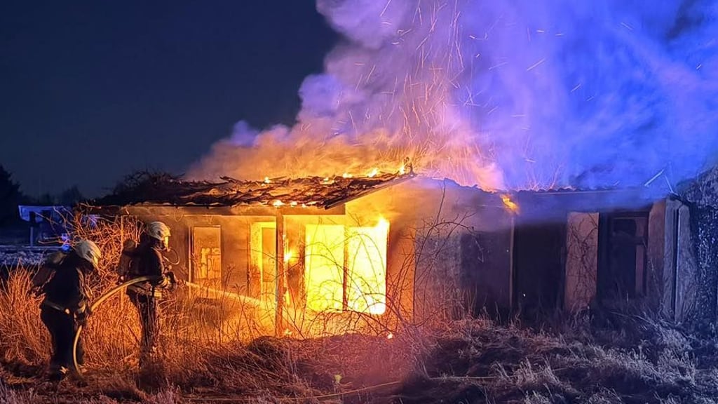 Flammen schlagen aus der freistehenden Gartenlaube – die Feuerwehr rückt mit fünf Fahrzeugen und 27 Einsatzkräften an.