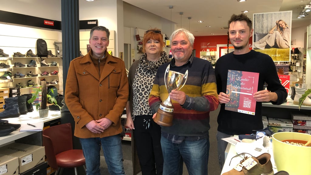 Das Schaufenster der "Schuh-Galerie" wurde beim "Zauber der Adventsstadt" in Quedlinburg zum schönsten gekürt. Inhaber Jörg Börner (2. v. r.) und Theo Naumann (r.) freuen sich über den Pokal, den Kathi Hennig, Vorsitzende der Kaufmannsgilde, gemeinsam mit Henry Thurisch, der die Aktion mit Nostalgiefotoapparaten unterstützte, übergeben  hat.