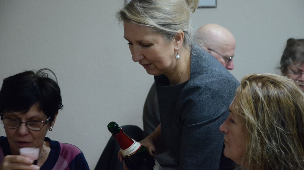 Bogumila Jacksch (M.), Ortsbürgermeisterin von Oebisfelde, schenkt Sekt ein im Dorfgemeinschaftshaus in Breitenrode, dessen Renovierung durch Ehrenamtliche aus dem Dorf ebenfalls mit Mitteln der Pro-Kopf Pauschale unterstützt werden konnte.