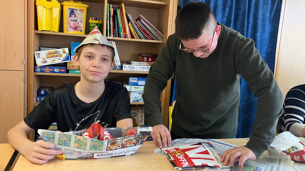 Denny und Dominik falten Boote aus der Tageszeitung.