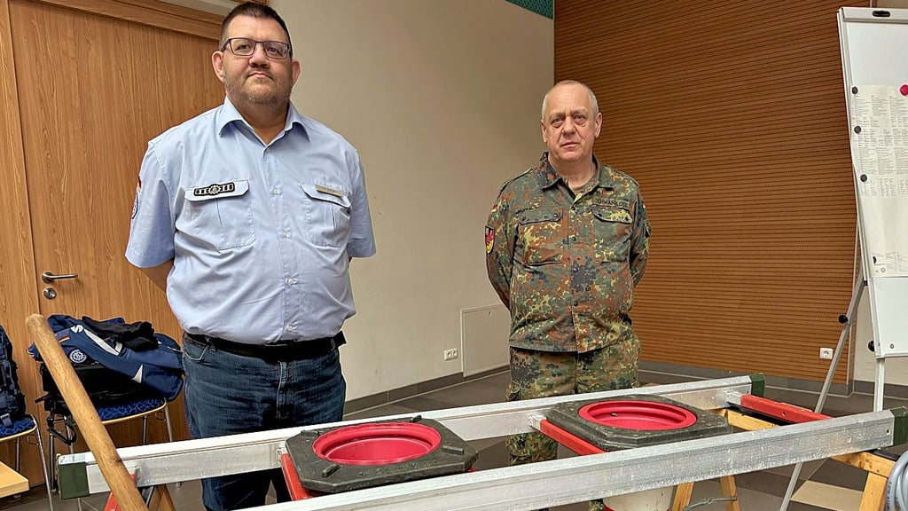 Christian Schulz vom Technischen Hilfswerk (THW) Burg und Thilo Schwarzlose vom Reservistenverband (r.) am Modell  einer Sandsackfüllstation. 