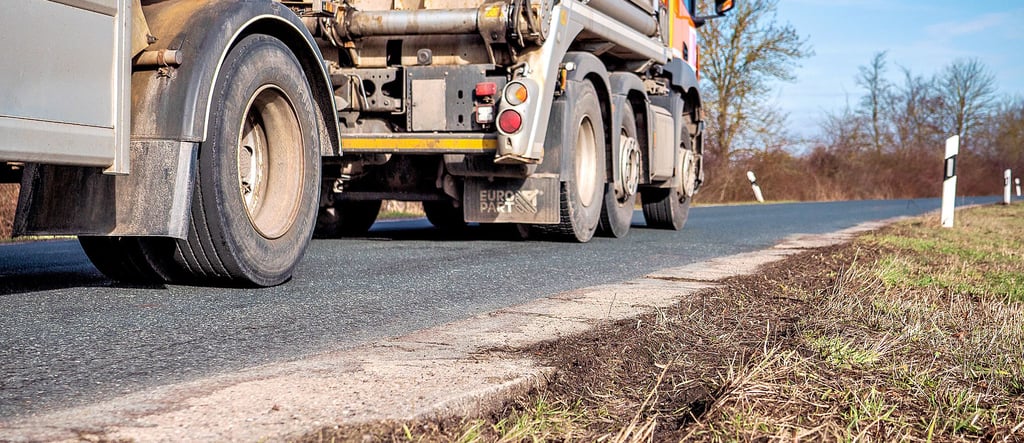Die Betonplatten am Rand der K1220 dienen als notdürftige Bankette. Sie sind vor allem in Kurvenbereichen heruntergefahren, da Lkw immer wieder auf den Randstreifen ausweichen müssen, weil die Straße zu eng ist.
