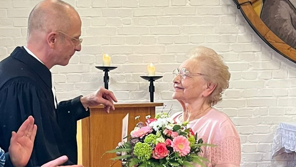 Ilse Brüser nimmt Blumen und Urkunde von Superintendent Jürgen Schilling entgegen.