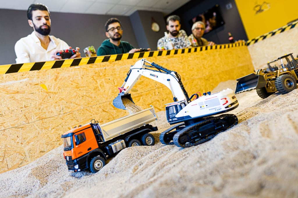 Gründer Siymo Othman (links) steuert mit Freunden kleine Bagger, Radlader und Lastwagen in seinem neu eröffneten Bagger-Café. Es soll das erste dieser Art in Deutschland sein.