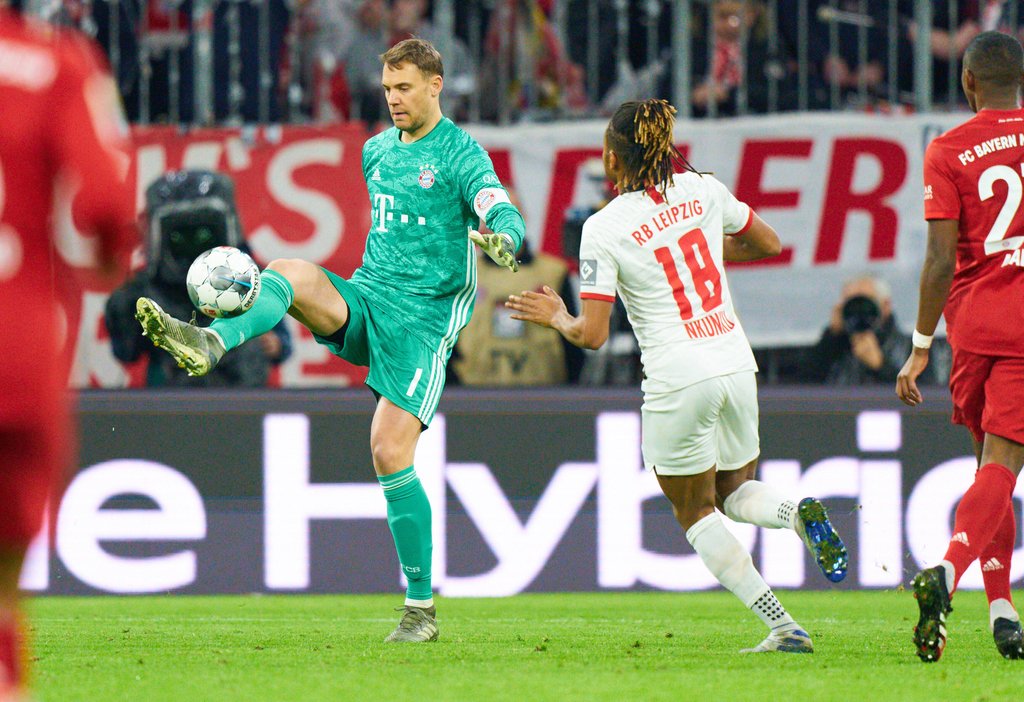 Manuel Neuer nimmt den Ball an, Christopher Nkunku von RB Leipzig lauert.