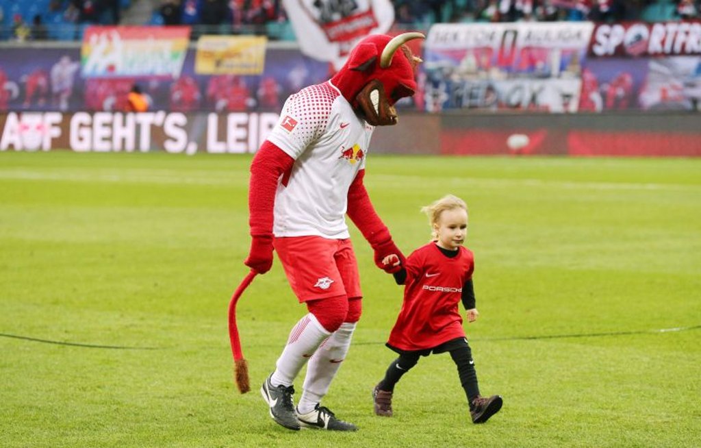 An der Hand von Maskottchen Bulli dürfen Kinder in der Red Bull Arena vor den Spielen von RB Leipzig mal auf den Rasen.