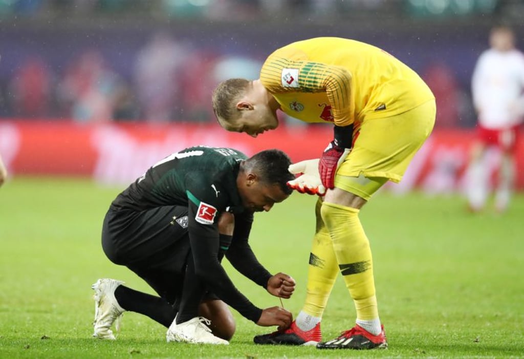 Von links: Alassane Plea bindet Torwart Peter Gulcsi die Schuhe zu.